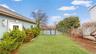 Expansive grassy lawn with manicured shrubbery bordering a light blue stucco exterior