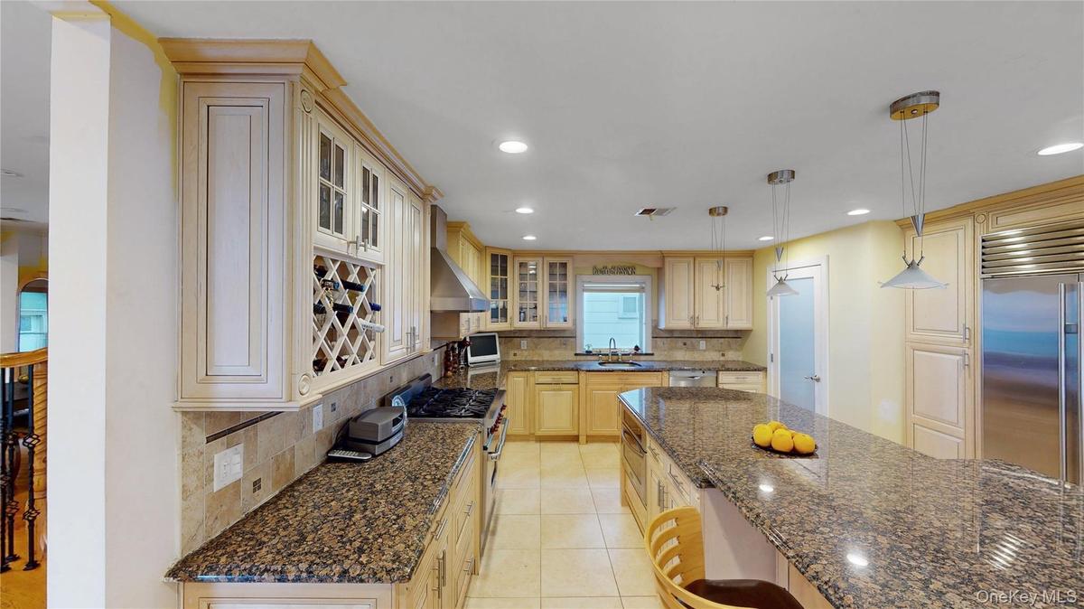 Spacious kitchen featuring light wood cabinetry, granite countertops, stainless steel appliances, a large center island, and recessed lighting