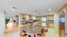 Spacious kitchen featuring an expansive island with a stone countertop, light wood-finish cabinetry, stainless steel appliances, and recessed lighting