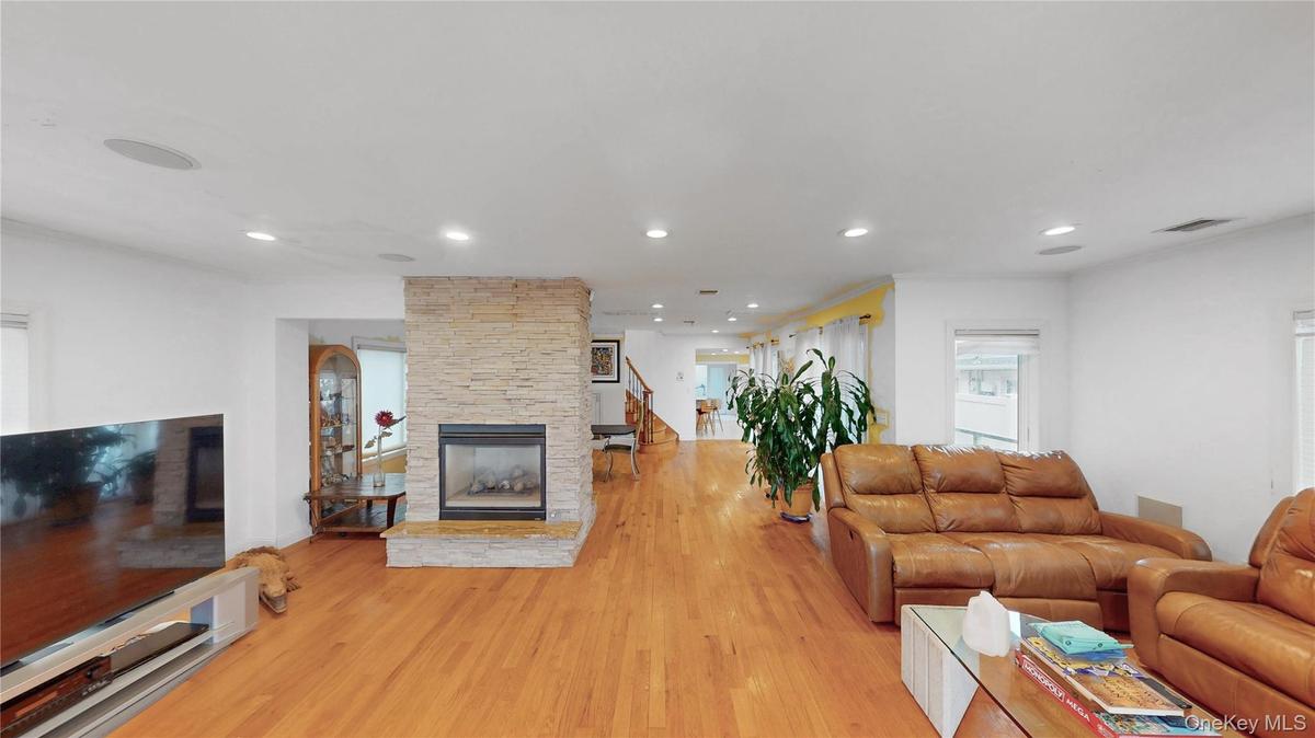 Living area featuring wood-finish flooring, a stone-clad fireplace, recessed lighting, and built-in ceiling speakers
