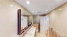 Bathroom featuring full-height tiled walls, recessed lighting, a dual vanity with undermount sinks, and a built-in mirrored cabinet