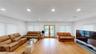 Spacious living area featuring light wood-finish flooring, recessed lighting, and multiple windows with blinds