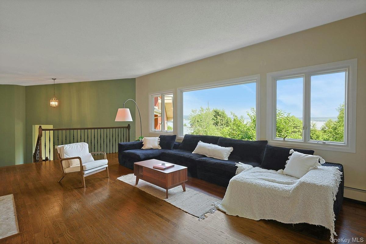 The expansive living room features large windows with views out to the beautiful front lawn and river beyond.