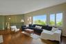 The expansive living room features large windows with views out to the beautiful front lawn and river beyond.