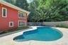 The well designed gunite pool is protected by a fence and ensconced by rows of trees.