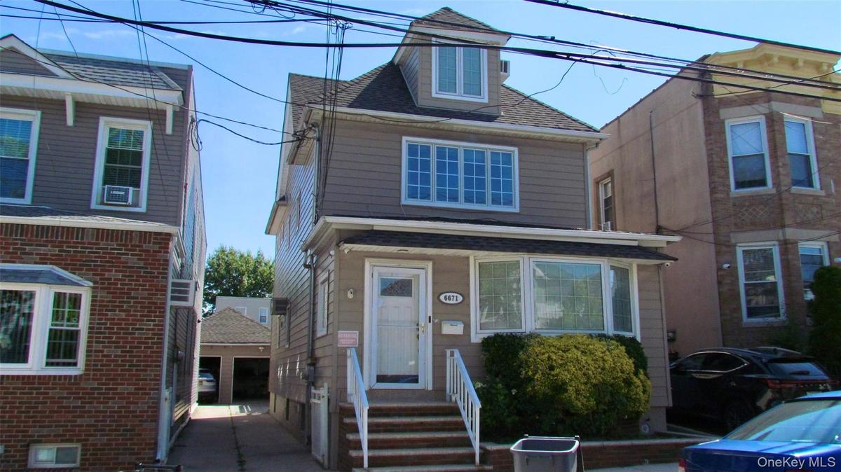 Three-story residence featuring light gray siding and a dormer window