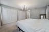 Spacious room featuring light gray walls, plush carpeting, a chandelier-style ceiling light, and multiple louvered bifold closet doors