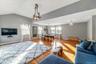 Spacious open-concept room featuring vaulted ceilings, wood-finish flooring, multiple windows with white curtains, and a decorative chandelier
