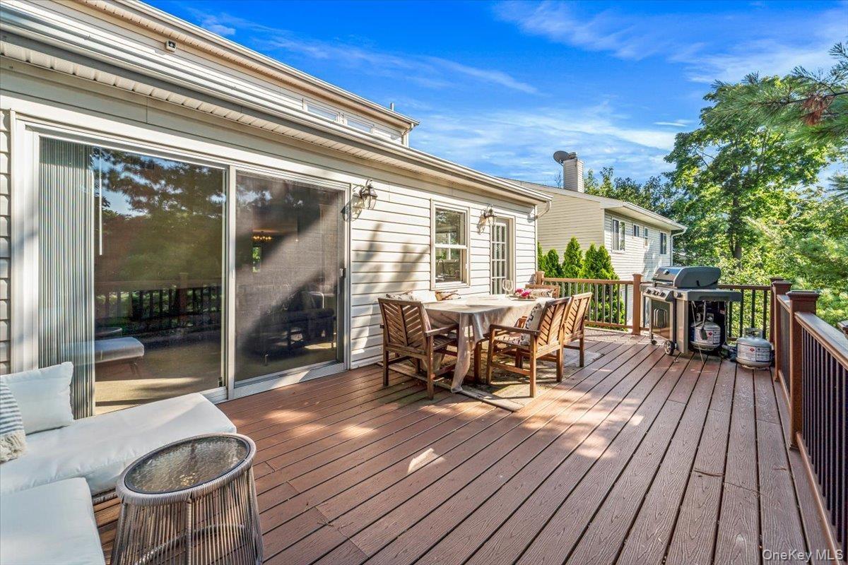 Deck with expansive seating and dinning areas accessed through glass sliding doors and separate back kitchen entrance