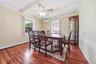 Spacious room featuring wood-finish flooring, two windows, and a ceiling fan with integrated lighting