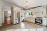 Kitchen featuring white cabinetry, stainless steel appliances, a crystal chandelier, wood-finish flooring, and a white tile backsplash