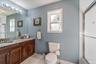 Bathroom featuring a dual-sink vanity with a stone countertop and wood cabinetry, a single window, and a shower with a sliding glass door