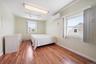 Room featuring wood-finish flooring, two windows, baseboard heating, a ceiling-mounted fluorescent light fixture, and a wall-mounted mini-split system