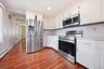 Kitchen featuring wood-finish flooring, white cabinetry, stainless steel appliances, and light countertops