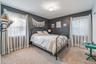 Carpeted room featuring a ceiling-mounted light fixture, two windows with curtain rods, and dark wall finishes