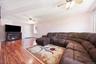 Spacious living area featuring wood-finish flooring, a ceiling fan, and a white entry door with frosted glass accents