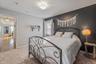 Carpeted room with a contrasting accent wall, ceiling-mounted light fixture, and a window with drapes