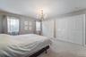 Carpeted room featuring a chandelier, two windows with draperies, and multiple louvered bi-fold closet doors