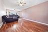 Spacious interior featuring wood-finish flooring, a ceiling fan with integrated lighting, and a bay window providing natural illumination