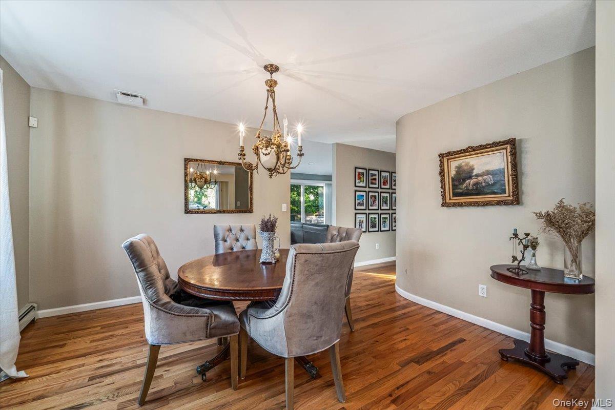 Dining area featuring hardwood flooring, a brass chandelier, a built-in wall niche, and an arched entryway