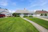 Charming ranch-style residence featuring a light gray exterior, a paved driveway, and a white picket fence