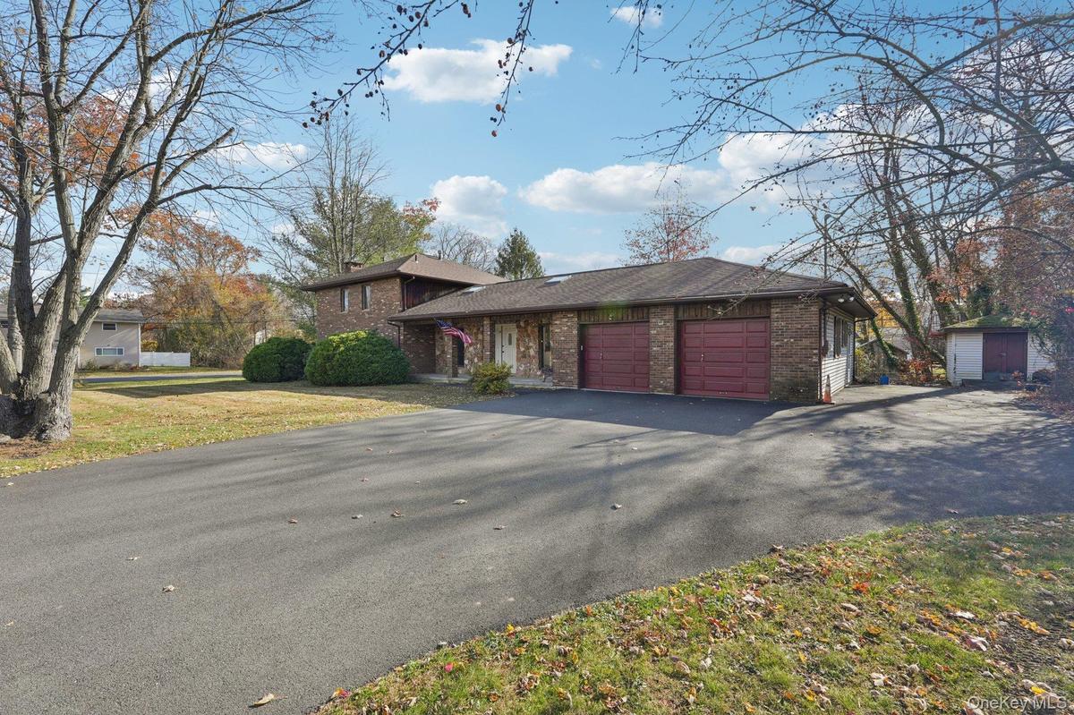 Split level home featuring brick siding, a garage, driveway, and a front yard