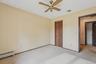 Unfurnished bedroom with carpet, baseboard heating, a ceiling fan, and a closet