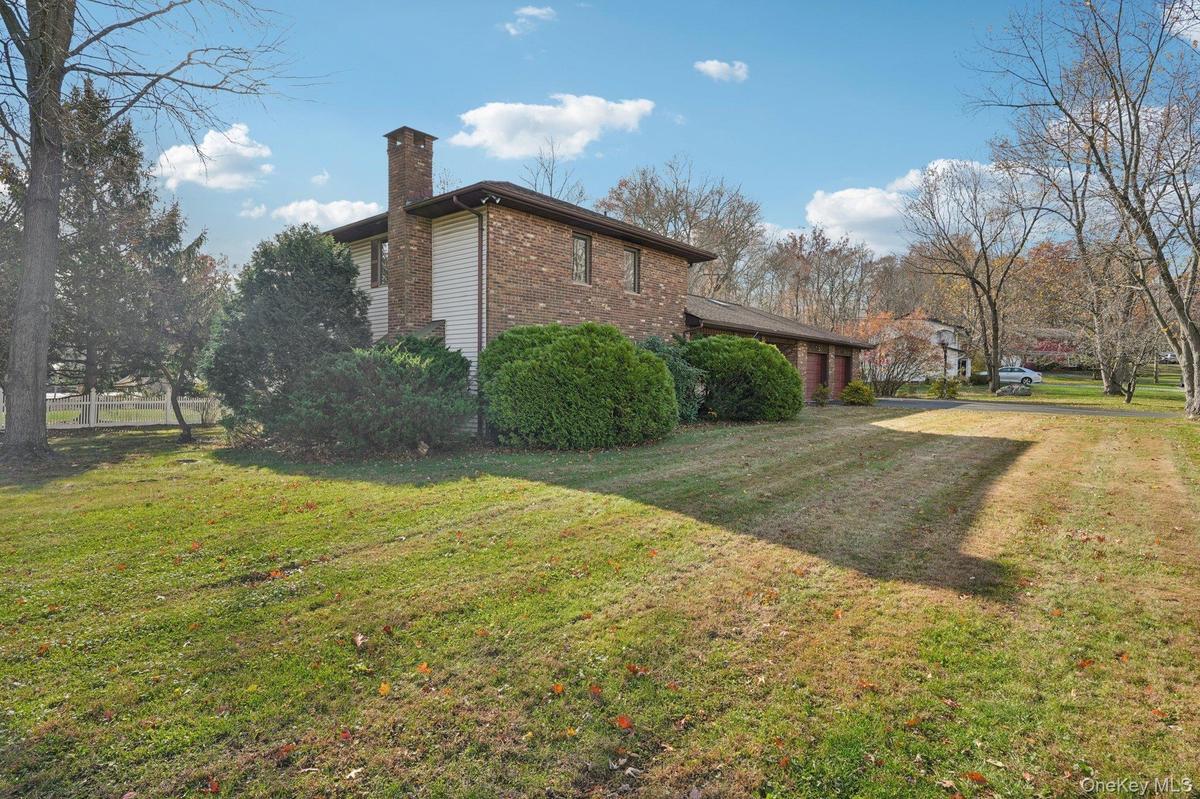 View of home's exterior with a chimney, a lawn, and brick siding
