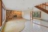 Unfurnished living room with a baseboard heating unit, light tile patterned floors, light carpet, and a stone fireplace