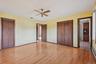 Unfurnished bedroom with two closets, light wood-style flooring, baseboard heating, and a ceiling fan