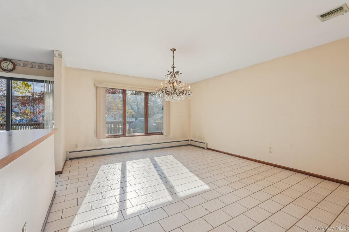 Spare room featuring baseboard heating, a chandelier, and light tile patterned flooring
