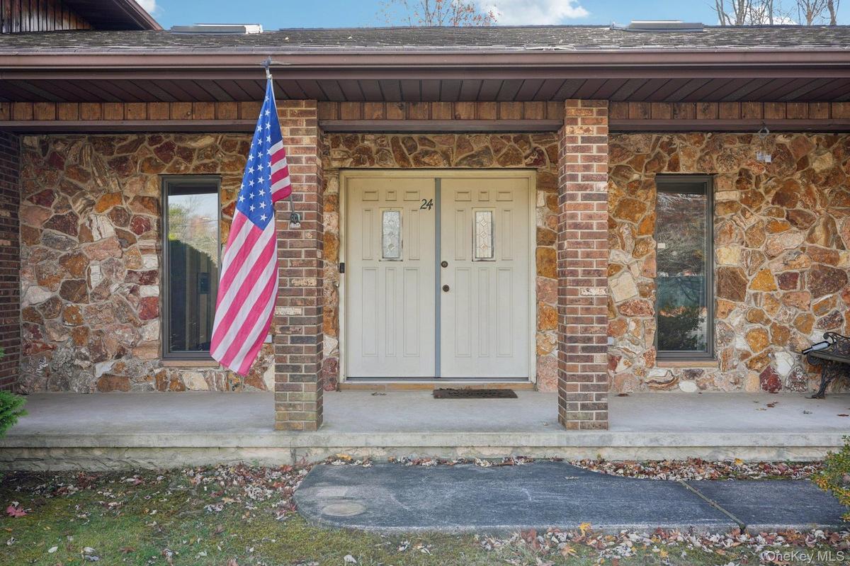 View of exterior entry featuring stone siding, a porch, and brick siding