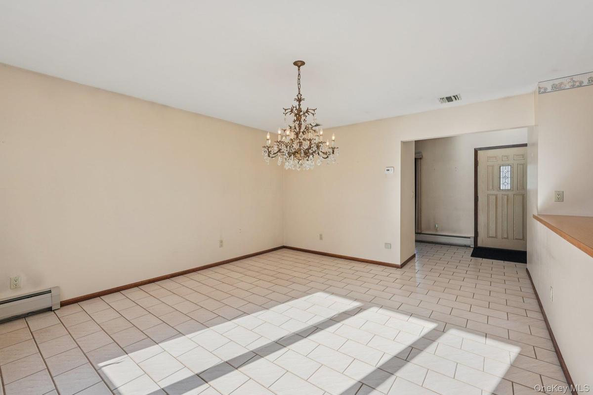 Unfurnished room with light tile patterned floors, a chandelier, and a baseboard heating unit