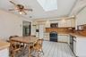Kitchen featuring black appliances, light countertops, a skylight, backsplash, and ceiling fan