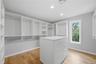 Walk-in closet with custom white shelving, multiple hanging rods, and a central island with integrated drawers