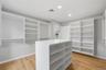 Spacious custom closet featuring extensive shelving, multiple hanging rods, a central storage island, recessed lighting, and wood-finish flooring