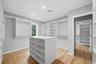 Spacious walk-in closet featuring extensive custom built-in shelving, hanging rods, a central storage island, wood-finish flooring, and recessed light