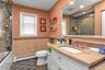 Full bathroom featuring dark tile patterned flooring, tile walls, vanity, a baseboard heating unit, and enclosed tub / shower combo
