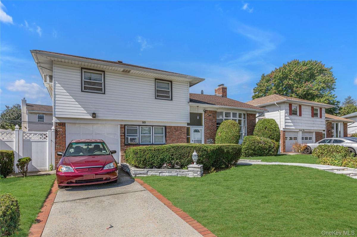 Split level home with brick siding, driveway, and a chimney