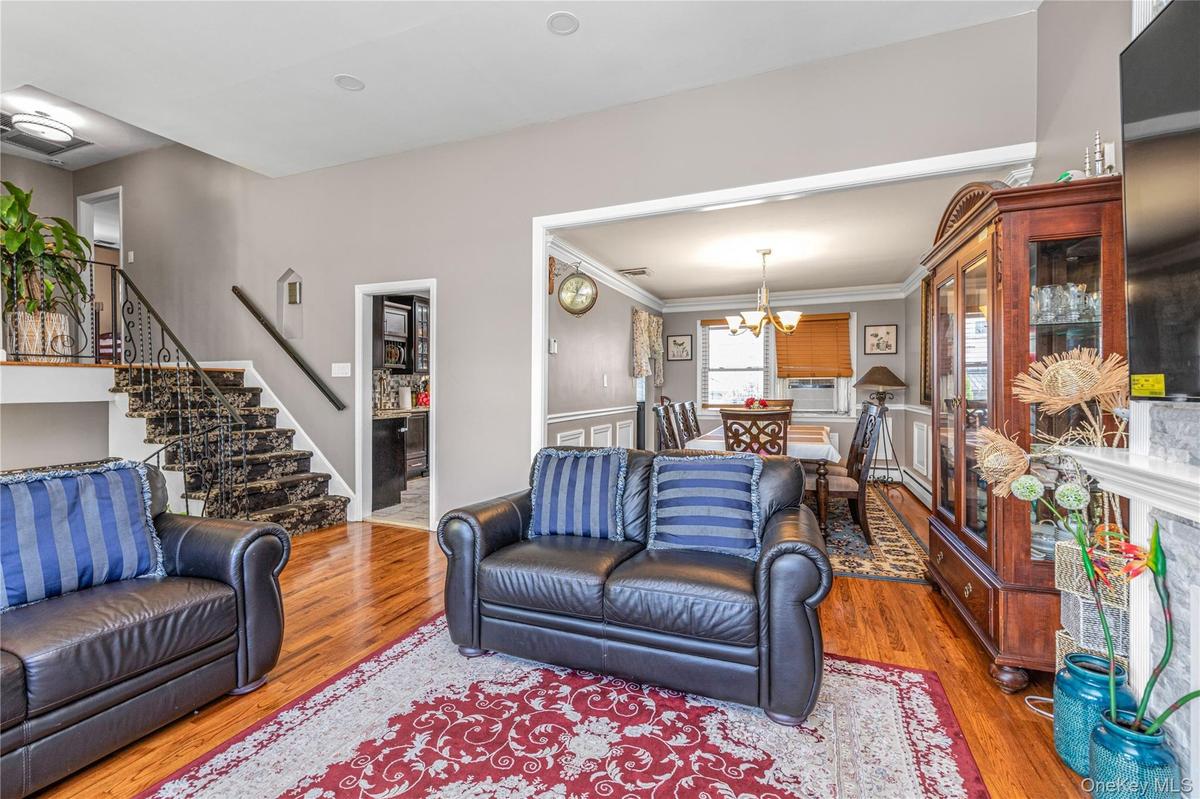 Living room with wood finished floors, stairway, a chandelier, and ornamental molding