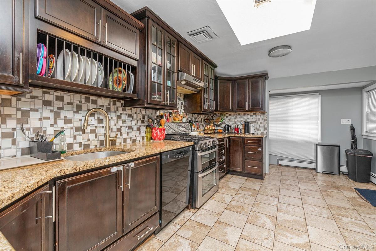 Kitchen featuring dark brown cabinetry, glass insert cabinets, light stone counters, tasteful backsplash, and range with two ovens