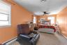 Carpeted bedroom with a baseboard radiator, multiple windows, and ceiling fan