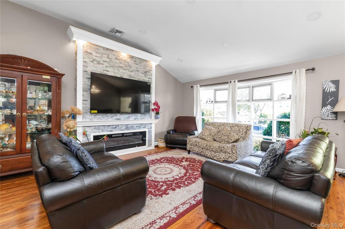 Living room featuring lofted ceiling, wood finished floors, and a stone fireplace
