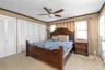 Bedroom with multiple closets, crown molding, light colored carpet, and ceiling fan