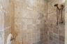 Hand-set stone and intricate mosaic accents bring warmth and character to this walk-in shower, evoking the feeling of a centuries-old European hideawa