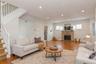 Spacious living area featuring polished wood flooring, a stone-clad fireplace, and recessed lighting (virtually staged)