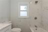 Bathroom featuring large format marble-look wall tiles, a built-in bathtub with brushed nickel fixtures, and a white framed window