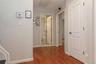 Hardwood-style flooring throughout hallway featuring light gray wall paint, white trim, and white paneled doors with arch details