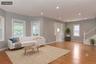 Open-concept living area featuring hardwood flooring, recessed lighting, multiple windows, a bay window, and a white staircase with balusters (virtual
