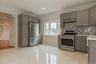 Kitchen featuring white marble-finish tile flooring, grey cabinetry, stainless steel appliances, a multi-tone tile backsplash, and a bay window